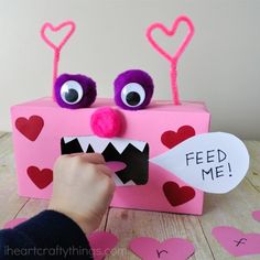 someone is making a valentine's day card out of a pink box with googly eyes