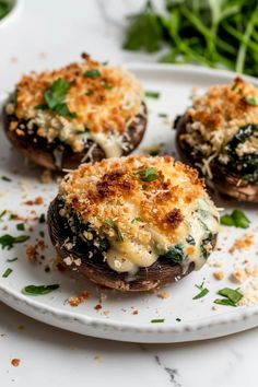 three stuffed mushrooms on a white plate with parmesan cheese and green vegetables in the background