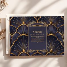 a card with an art deco design in gold and blue on the front, next to some dried flowers