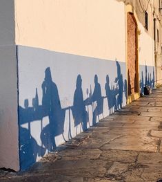 shadows cast on the side of a building as people sit at a table in front of them