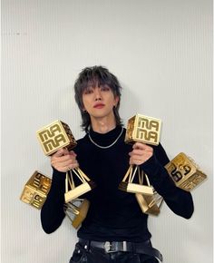 a person holding up some gold objects in their hands and posing for the camera with one hand