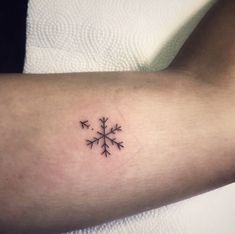 a small snowflake tattoo on the arm