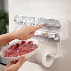 a person holding a bowl of strawberries in front of a paper towel dispenser