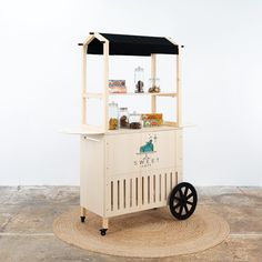 an ice cream cart sitting on top of a wooden floor next to a white wall