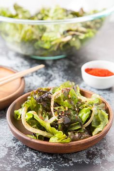 a wooden bowl filled with lettuce next to another bowl full of lettuce