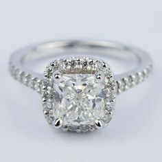 an engagement ring with a cushion cut diamond in the center and pave set shoulders