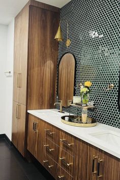 a bathroom with wooden cabinets and white counter tops, gold accents on the mirror above the sink