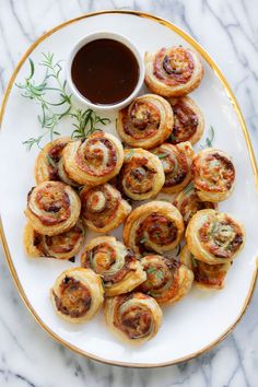 a white plate topped with pastry rolls next to a cup of coffee on top of a marble table