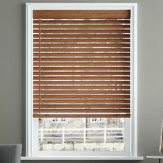 a living room with grey walls and wooden blinds on the window sill in front of it