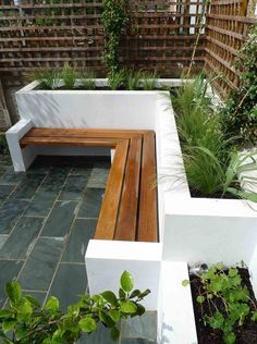 a wooden bench sitting in the middle of a garden next to a planter filled with potted plants