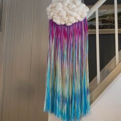 a multicolored wind chime hanging from the side of a stair case next to a window