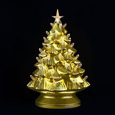 a lighted gold christmas tree with angel wings on it's base, against a black background