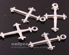 four silver cross charms on a black surface