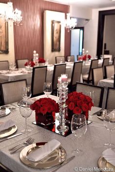 the table is set with silverware and red roses