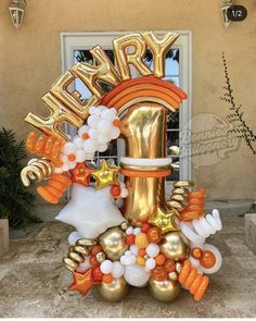 a large number one balloon sculpture in front of a door with balloons and decorations around it