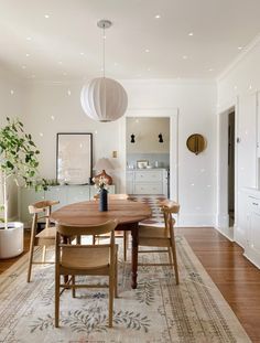 a dining room table with chairs and a rug on the floor in front of it