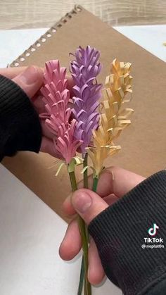 a person is holding some flowers in their left hand and the other one has paper on it