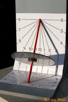 a close up of a clock with a red arrow in it's center and numbers on the sides