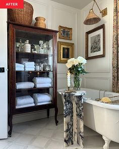 a bath room with a tub a sink and some pictures on the wall above it