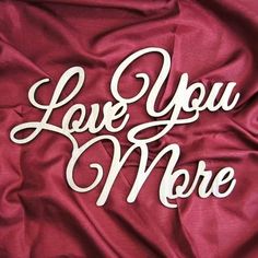 the words love you more are in white letters on a red cloth