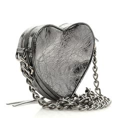 This is an authentic BALENCIAGA Metallic Agneau Arena Le Cagole Mini Heart Bag in Silver. This stylish and structured handbag is crafted of silver metallic lambskin leather. The bag features a silver link shoulder strap and a top zipper, and a front zipper pocket. The top unzips to a black fabric compact interior with card slot pockets. Bag Silver, Heart Bag, Mini Heart, Lambskin Leather, Black Fabric, Front Zipper, Zipper Pocket, Metallic Silver, Balenciaga