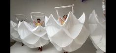 three women in white dresses are hanging upside down