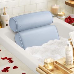 a bathtub filled with foam next to candles and rose petals on the counter top