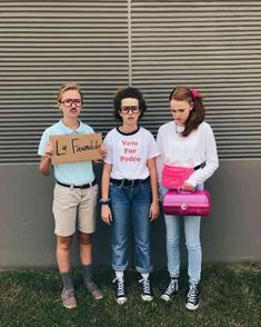 three people standing next to each other holding signs