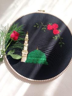 a black round wall hanging with red flowers and a green dome on it's side