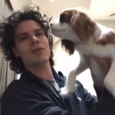 a man holding a dog in his arms and looking up at the camera while standing next to him