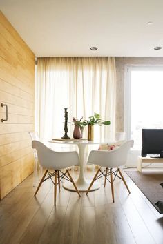 two white chairs sitting at a table in front of a window next to a tv