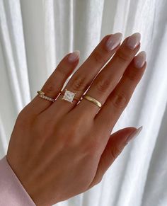 a woman's hand with three different rings on her left and the middle finger