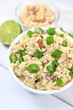 two bowls filled with food sitting on top of a white table next to limes