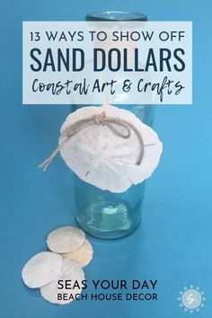 a glass vase filled with sand dollars sitting on top of a blue table