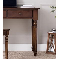 a desk with a laptop on top of it next to a chair and side table