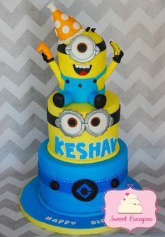 a three tiered cake decorated like a minion with a birthday hat on top