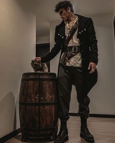 a man standing next to a barrel with a cat on it