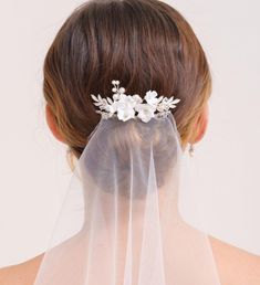 the back of a woman's head wearing a veil with flowers on it,