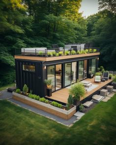 a house made out of shipping containers in the middle of some grass and plants on top of it