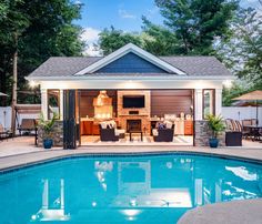 a pool house with an outdoor kitchen and dining area next to the pool is lit up at night