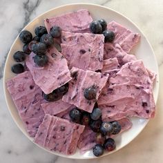 a white plate topped with blueberries and fudges on top of a marble counter