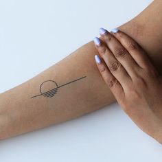 a woman's arm with a small sun tattoo on the left side of her arm