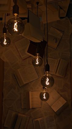 several light bulbs are hanging from the ceiling in front of books and notebooks on top of a table