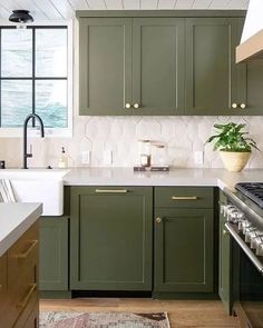 a kitchen with green cabinetry and white counter tops, along with a rug on the floor