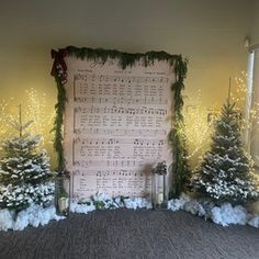 christmas trees and sheet music on display in front of a bulletin board with lights behind them