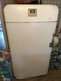 an old white refrigerator sitting next to a basket on top of the freezer door