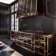 an ornate kitchen with black cabinets and gold trim on the doors, stove hoods and drawers