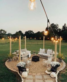 an outdoor seating area is lit up with lights and flowers in the middle of it