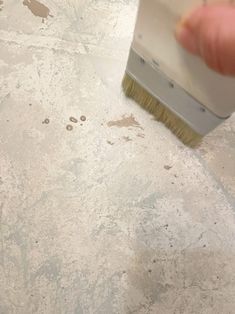 a person using a brush to paint a floor with white and brown stains on it