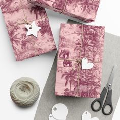 pink wrapping paper with white hearts and an elephant on it next to twine of scissors